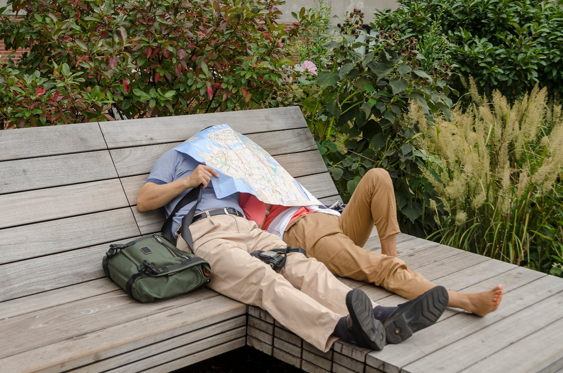 person in brown pants and gray shoes sitting on white wooden bench