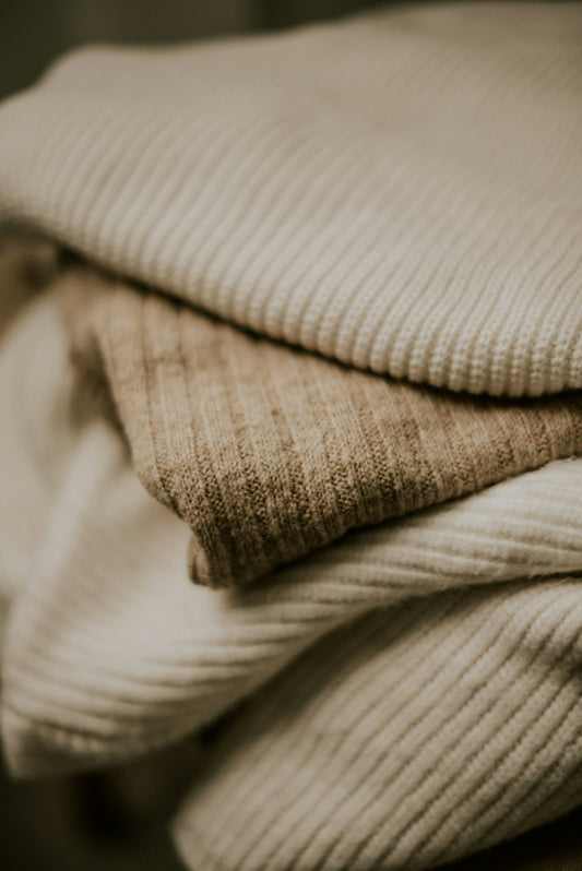a stack of folded blankets sitting on top of a wooden table