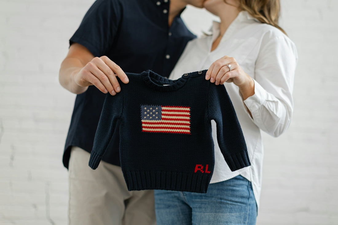 Couple holding a baby sweater with american flag.